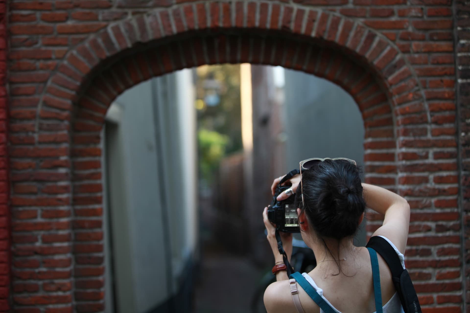 Photographer composing a street scene through a brick arch in Leiden