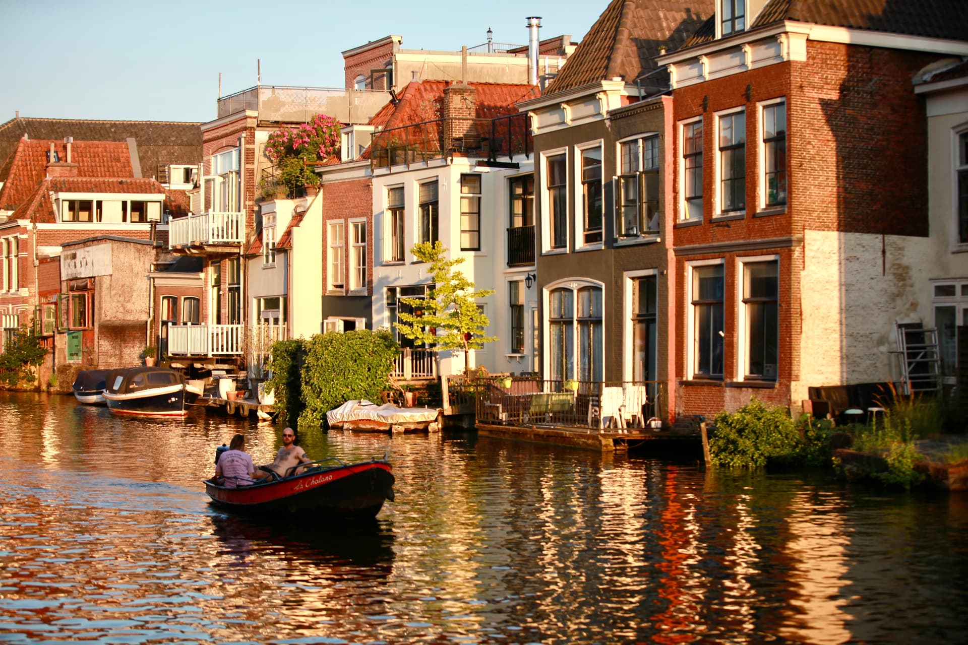 A small boat crossing a sunlit canal in historic Leiden