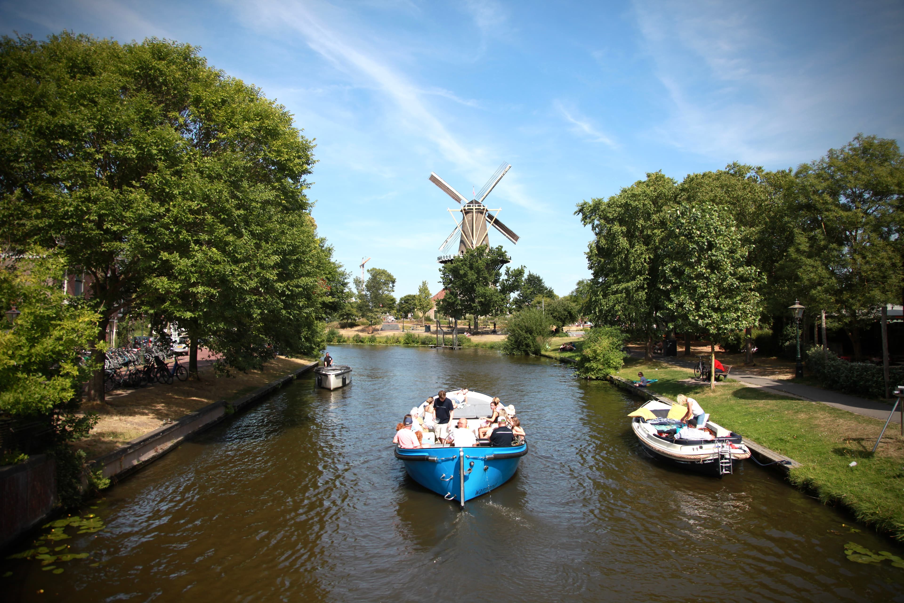 Boats approaching a Leiden windmill on a sunny canal