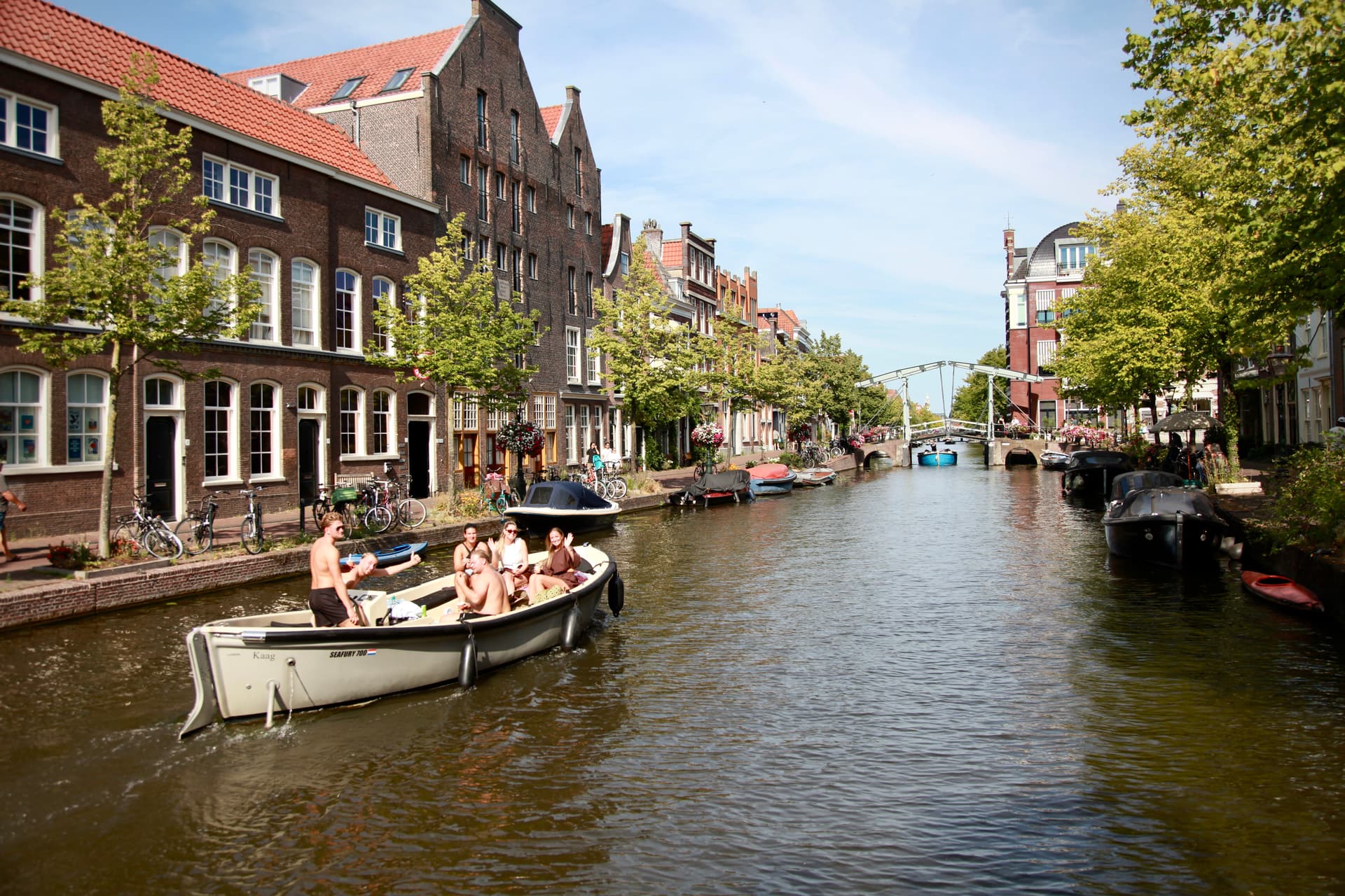 Boaters passing historic houses on a Leiden canal
