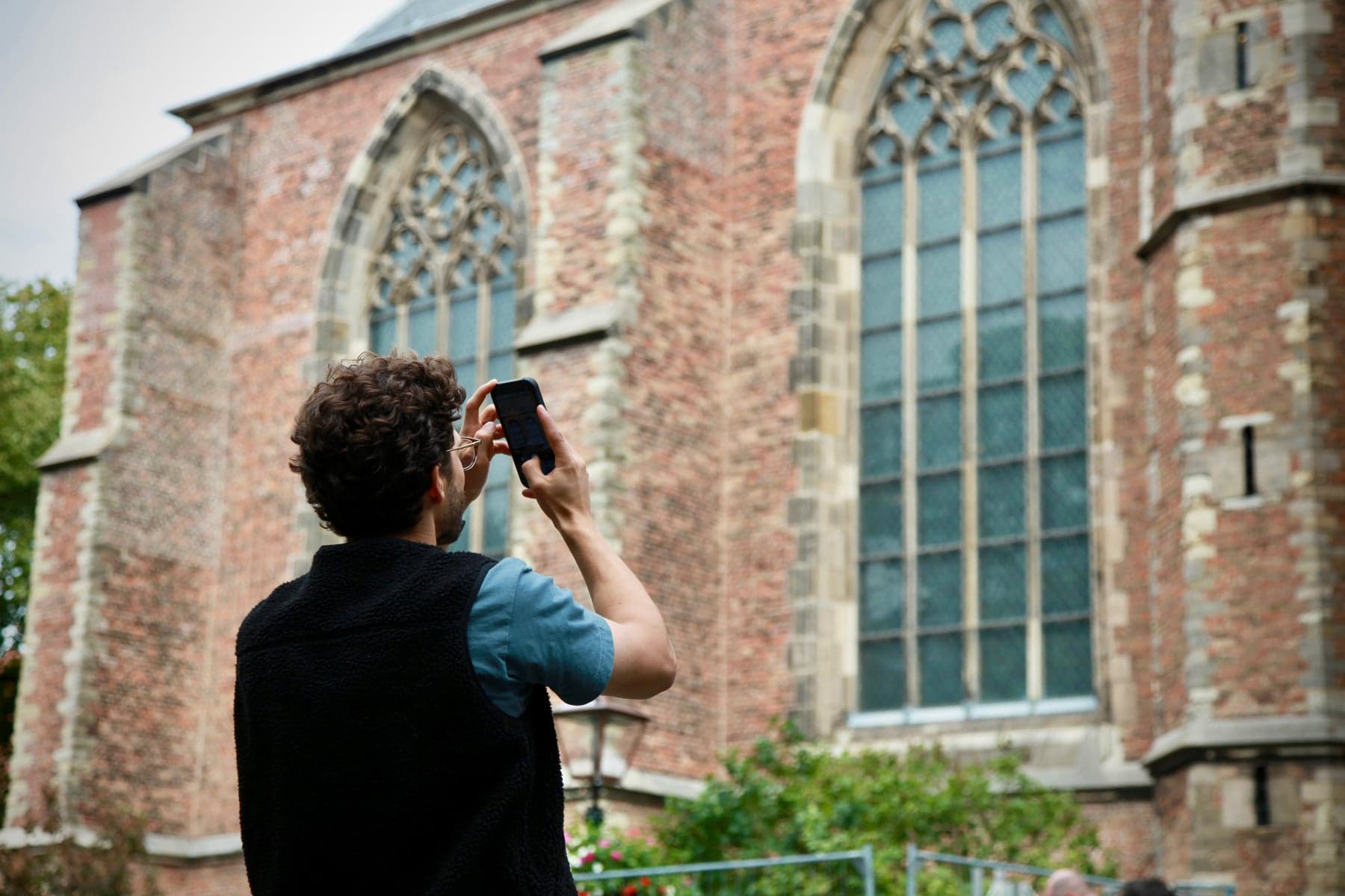 A participant photographing historic church windows with a smartphone in Leiden