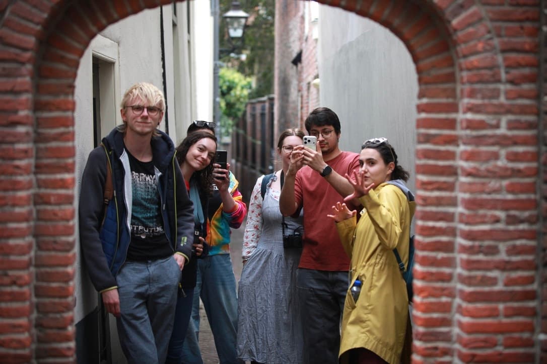 A photo tour group with phones and cameras beneath a brick arch in Leiden